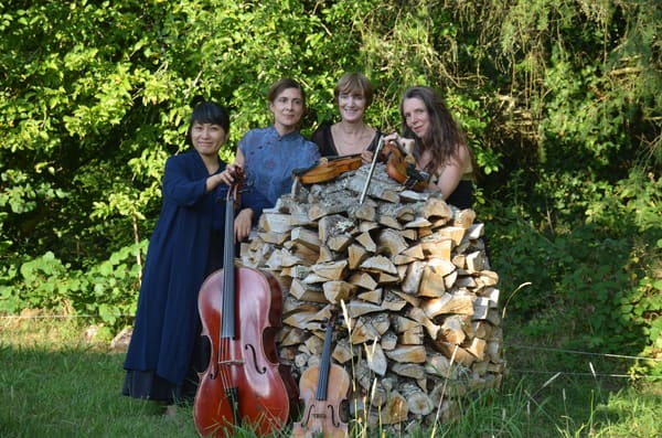Le Quatuor Fabula autour d’un tas de bois, en forêt